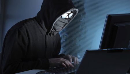 hooded cyber criminal hacking a computer